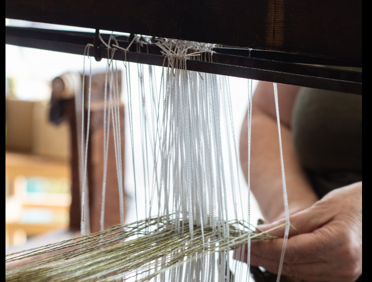 weaver at loom close up on hands and theads