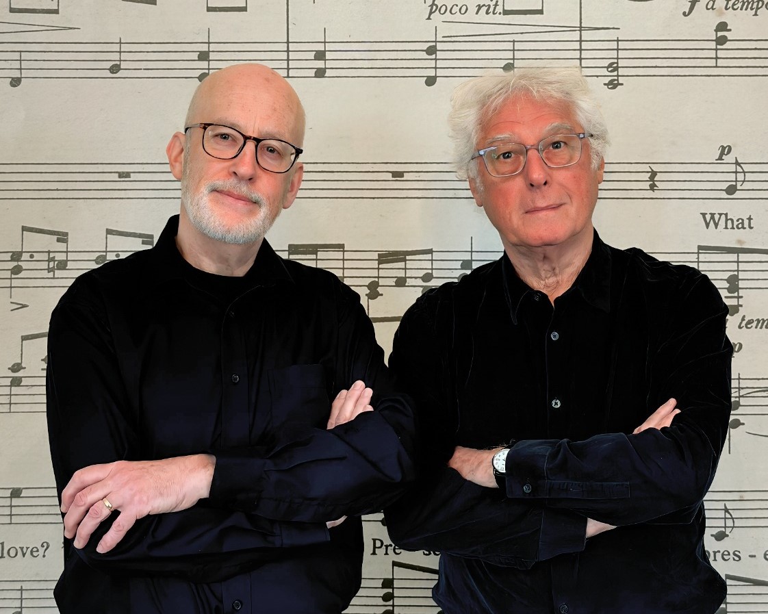 two men in black with sheet music background